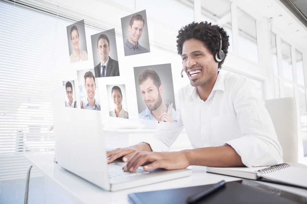 Happy businessman working at his desk wearing headset against profile pictures